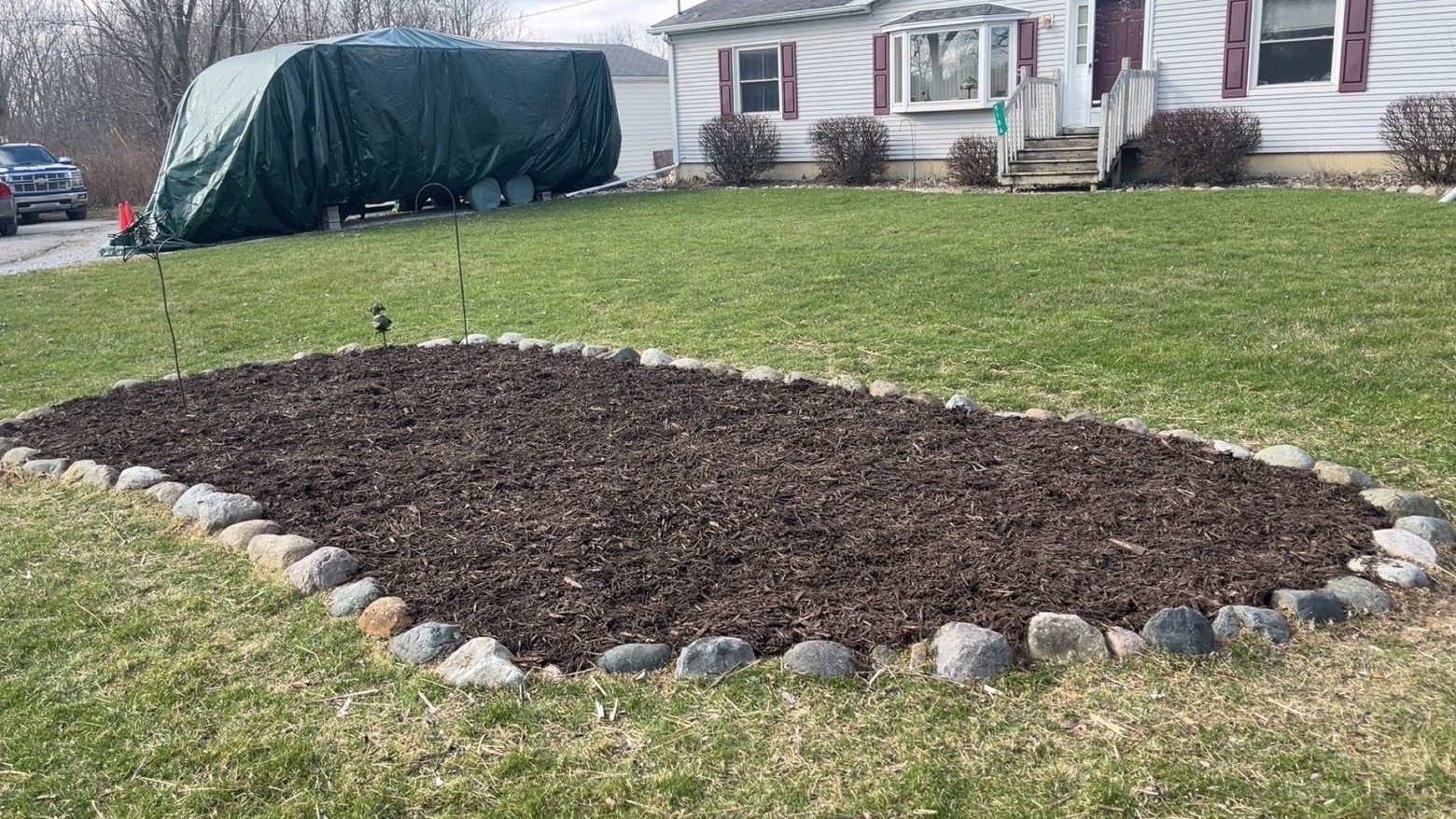 After: freshly installed mulch bed edged with natural stone